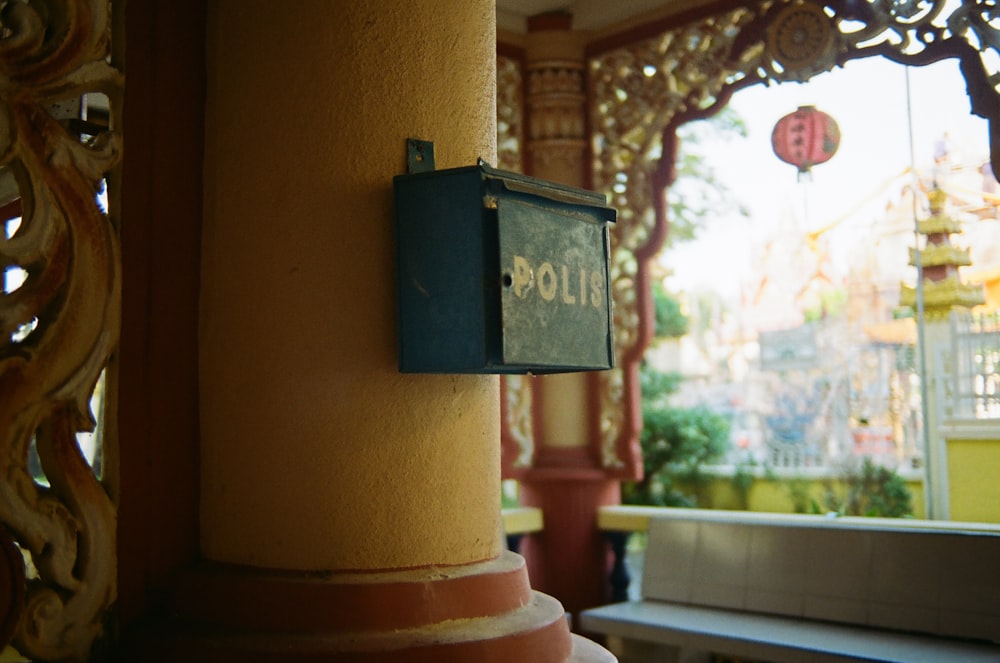 black and white wooden box mounted on brown concrete post