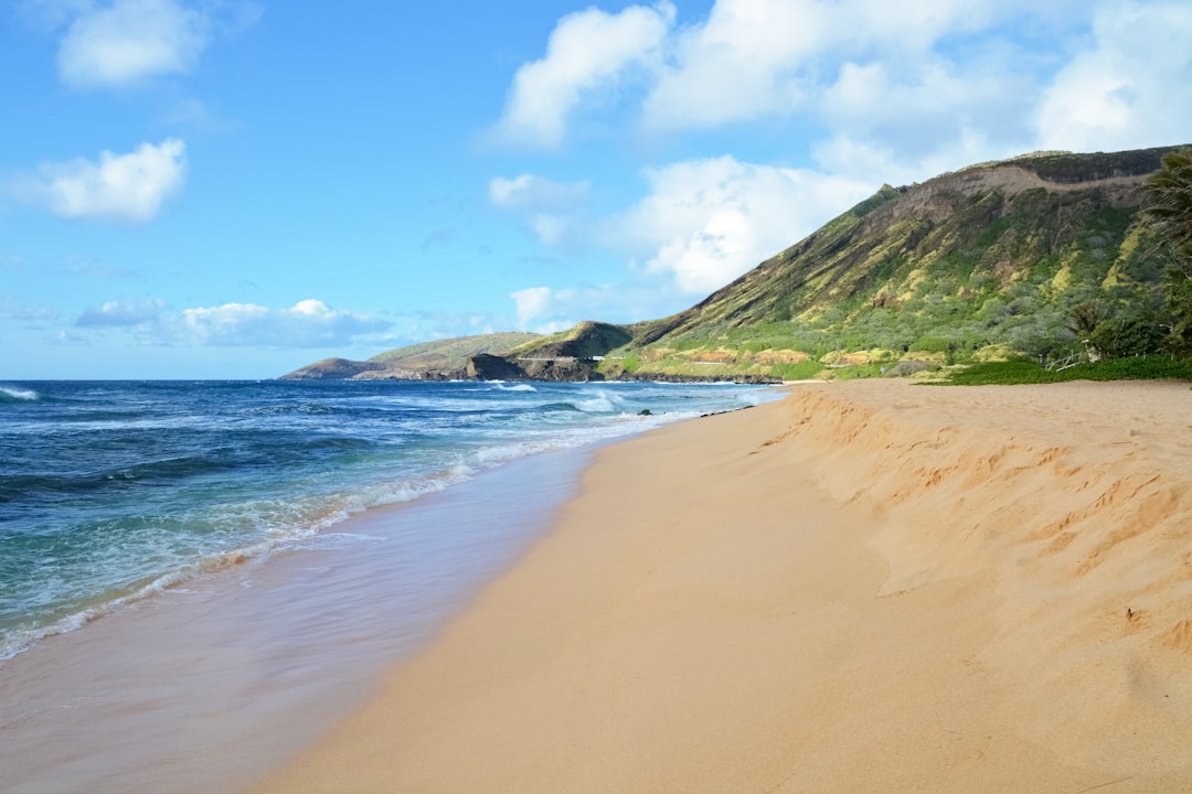 green mountain beside sea under blue sky during daytime