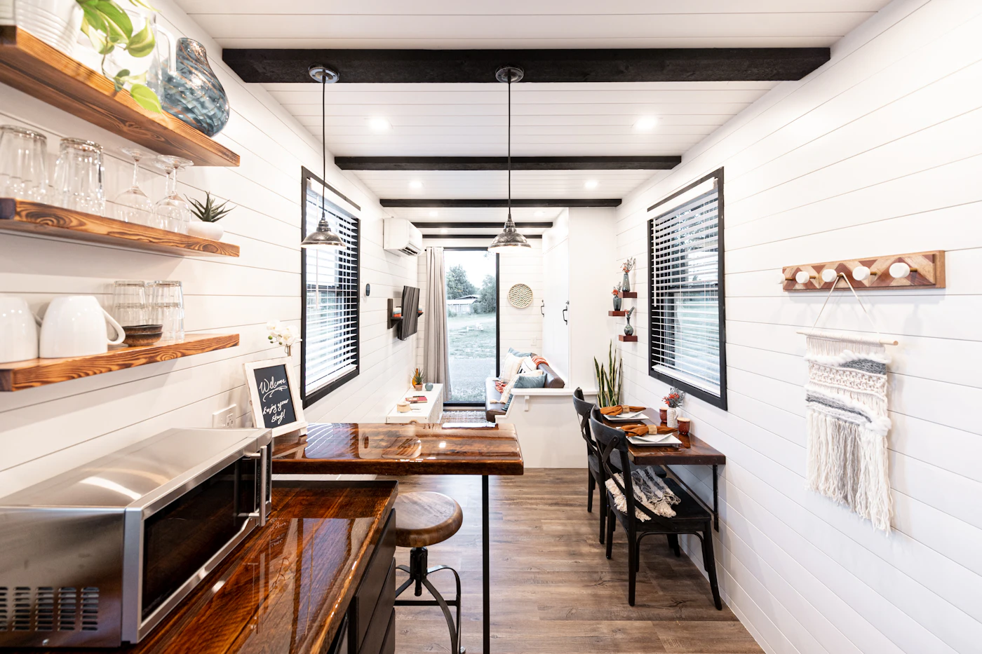 Bright container home interior with white walls, wood table and galley layout