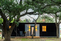 brown wooden house near green tree during daytime