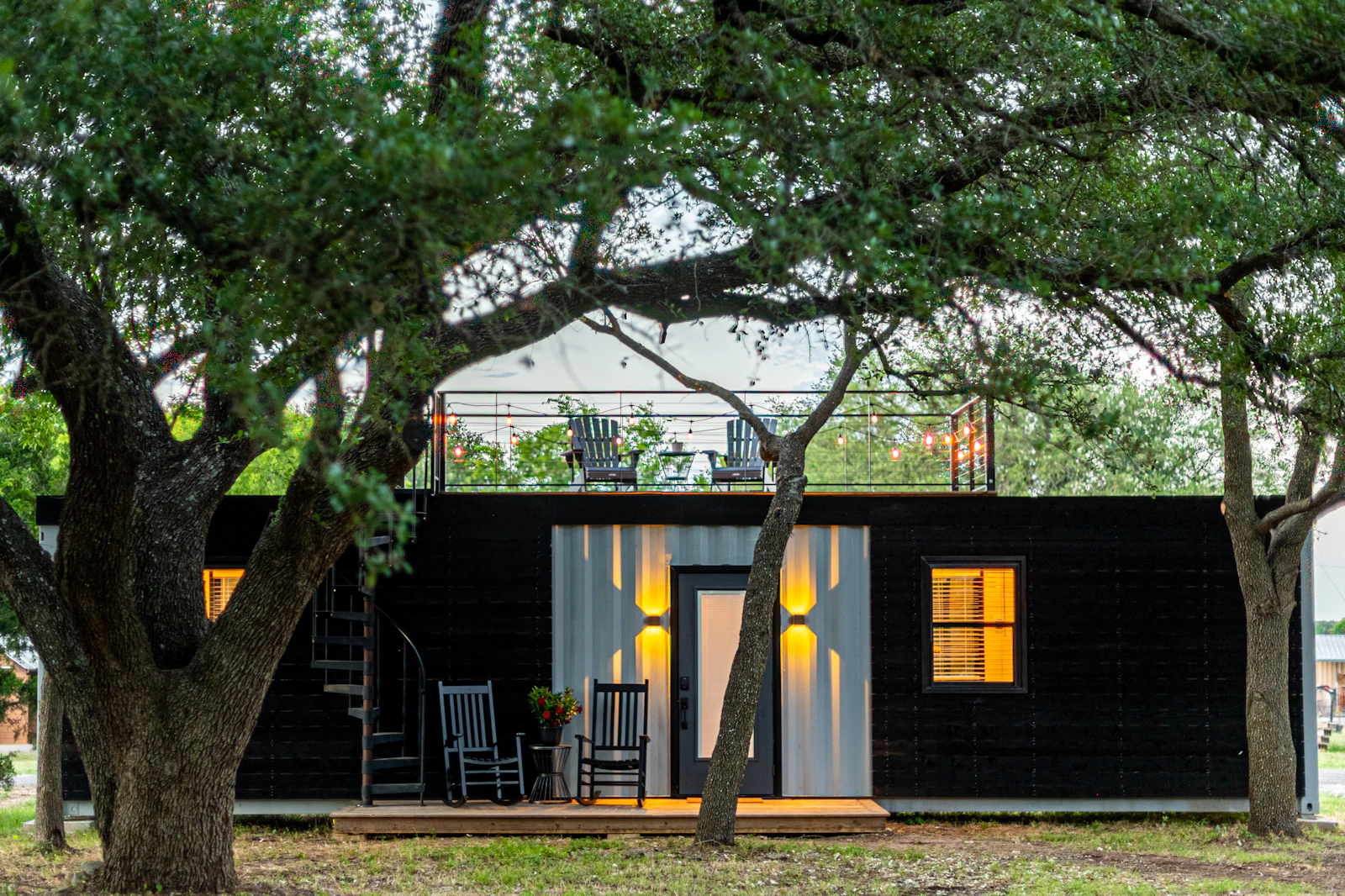 Modern luxury tiny home exterior with wood siding near a green tree
