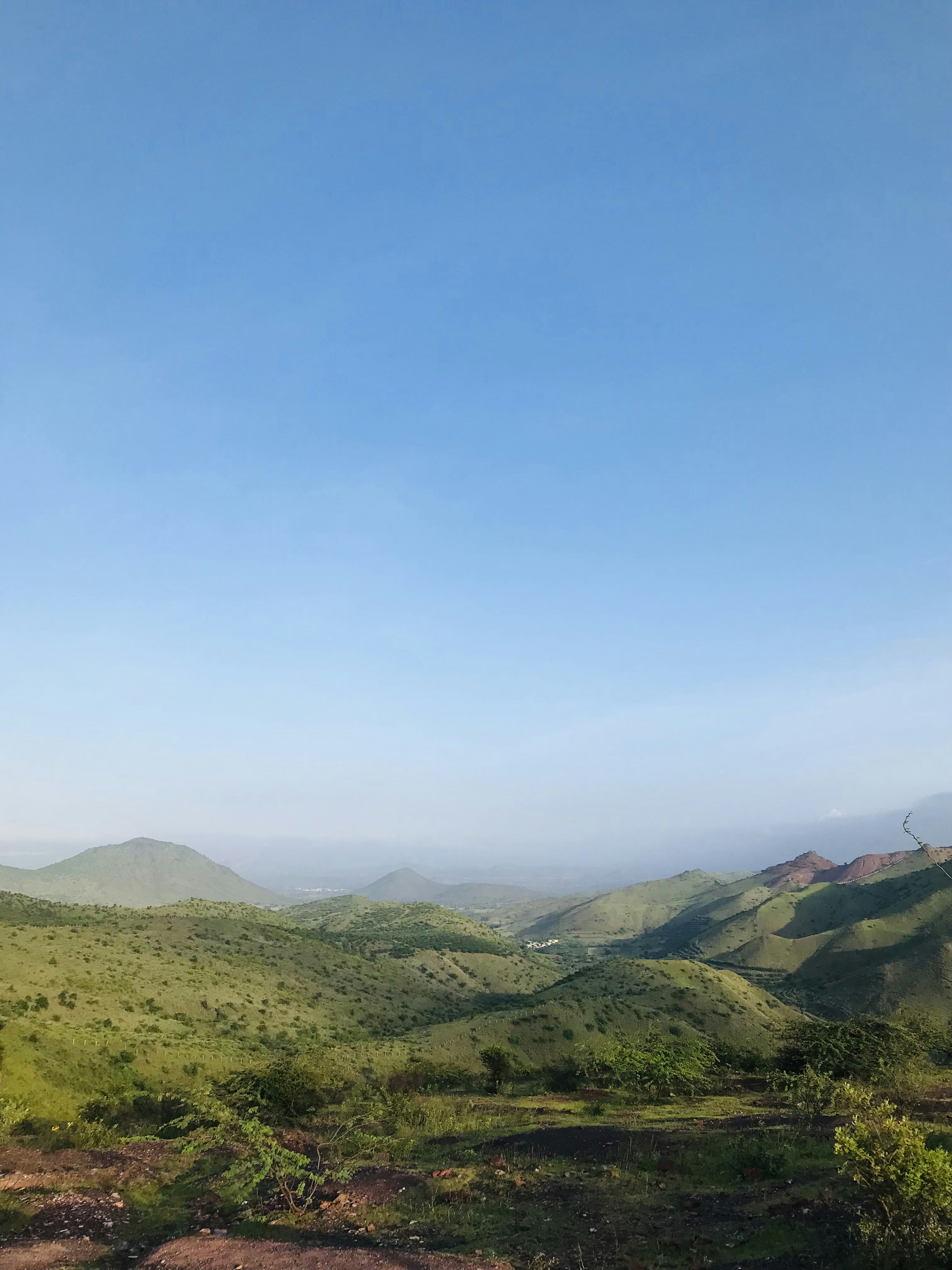 green grass field and mountains under blue sky during daytime