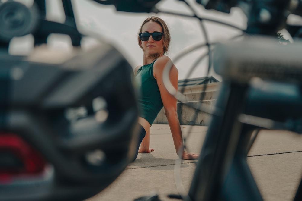 woman in green tank top and black shorts standing beside black car during daytime