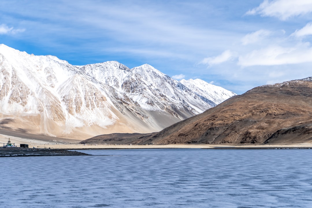 snow covered mountains near body of water during daytime