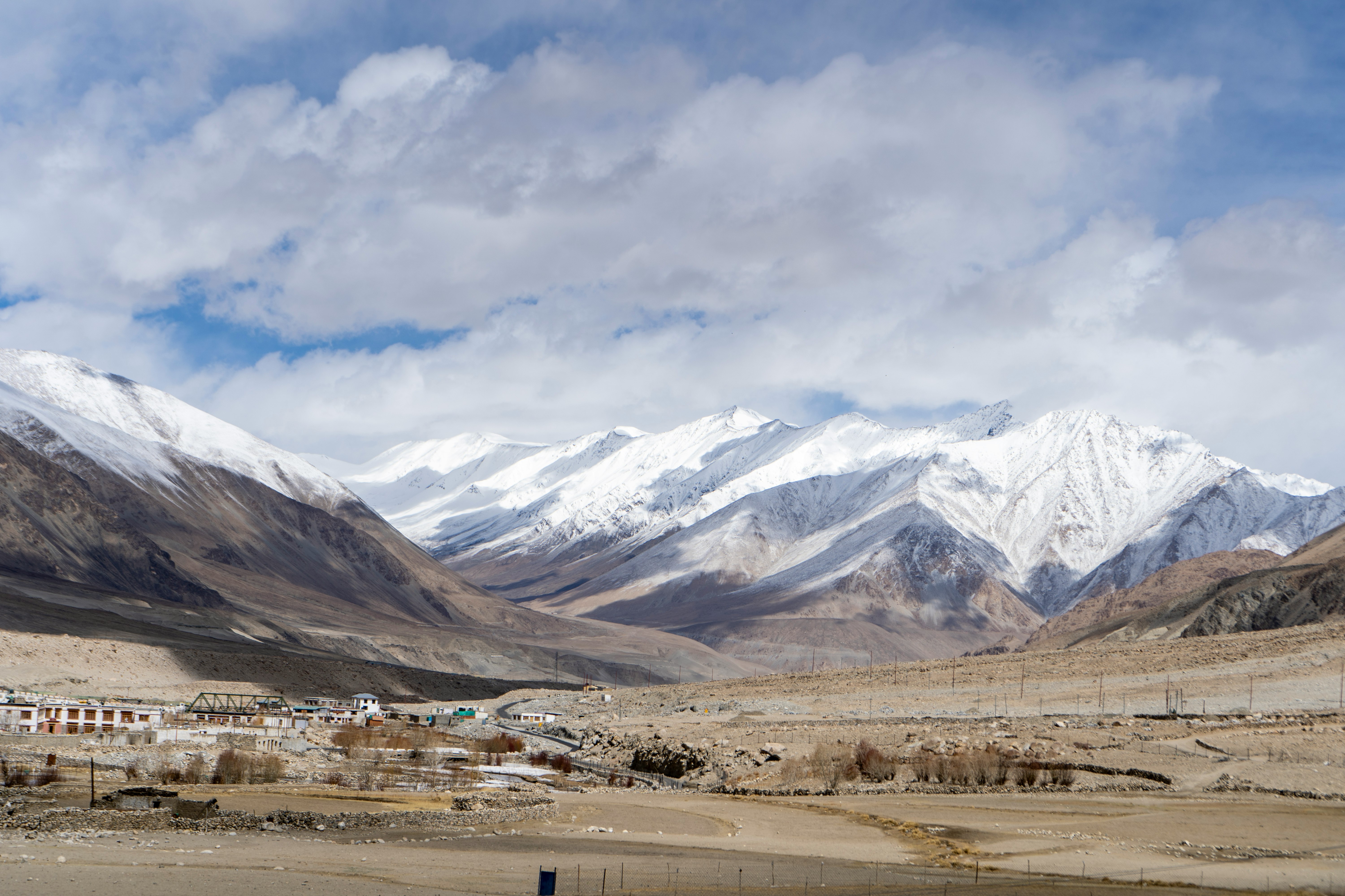 white and brown mountains under white clouds and blue sky during daytime