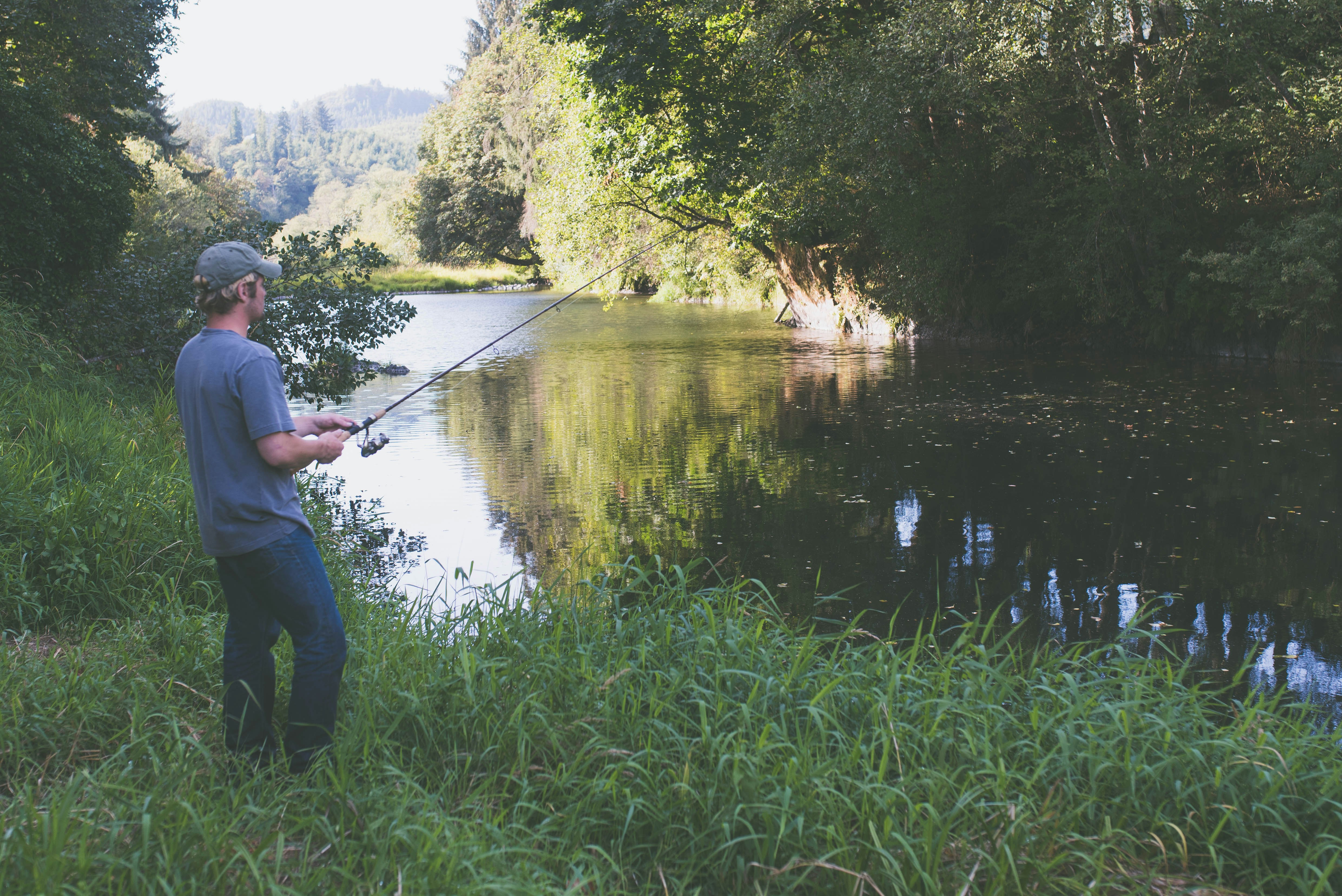 Man in blue shirt fishing on lake during daytime photo Free Hebo Image on Unsplash