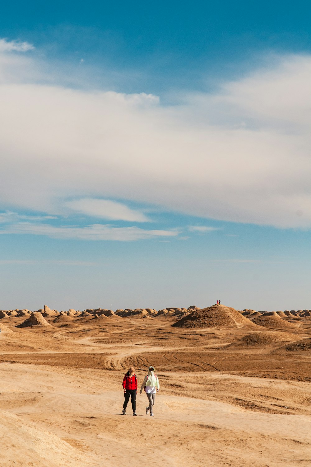 Person im weißen Hemd geht tagsüber auf braunem Sand unter blauem Himmel