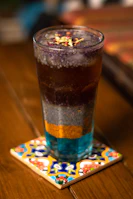 A colorful sensoryta beverage with a layered look, set in a sleek glass under warm lighting