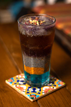 A colorful sensoryta beverage with a layered look, set in a sleek glass under warm lighting