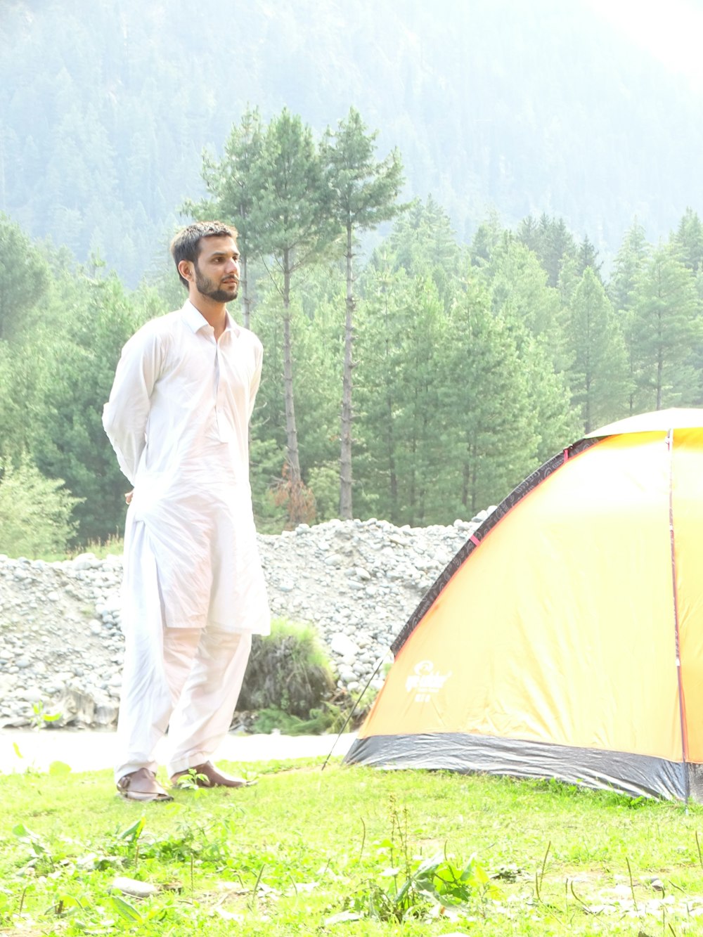 man in white thobe standing near yellow tent during daytime