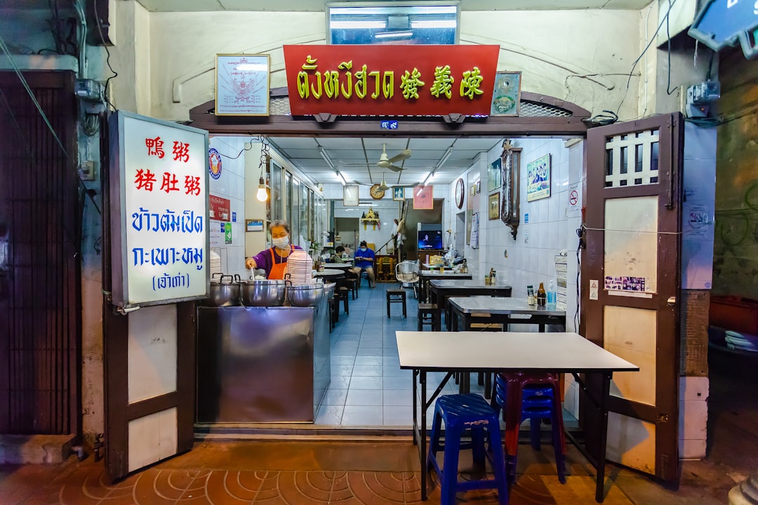 brown wooden table near white wall, The old shophouse Tang Ngee Huad in Bangkok. Come here for jok (congee) rice porridge with duck.<p></figure>