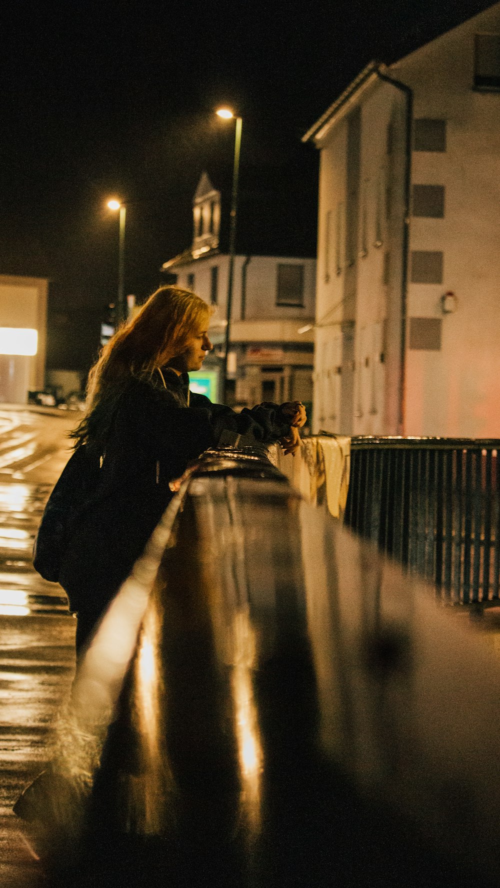 woman in black coat standing on sidewalk during night time