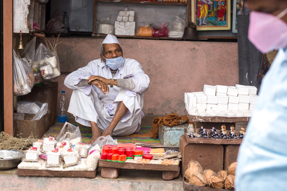 man in white thobe sitting on brown wooden table