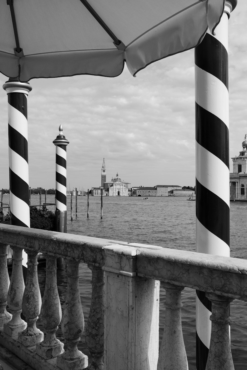 grayscale photo of us flag on wooden fence near body of water