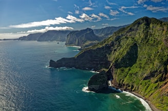 green and brown mountain beside body of water during daytime