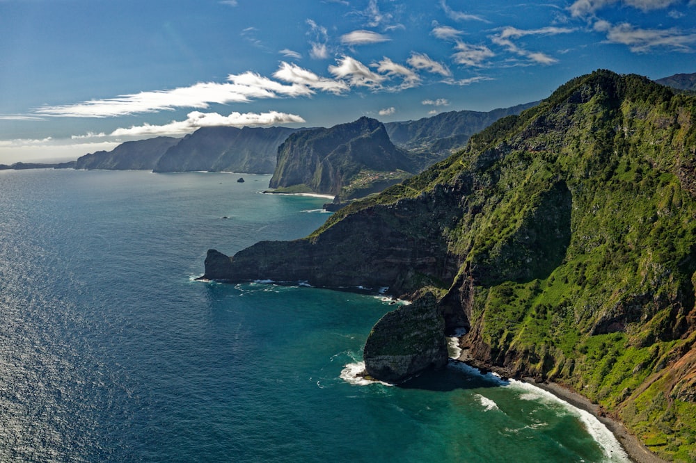 Montaña verde y marrón al lado del cuerpo de agua durante el día