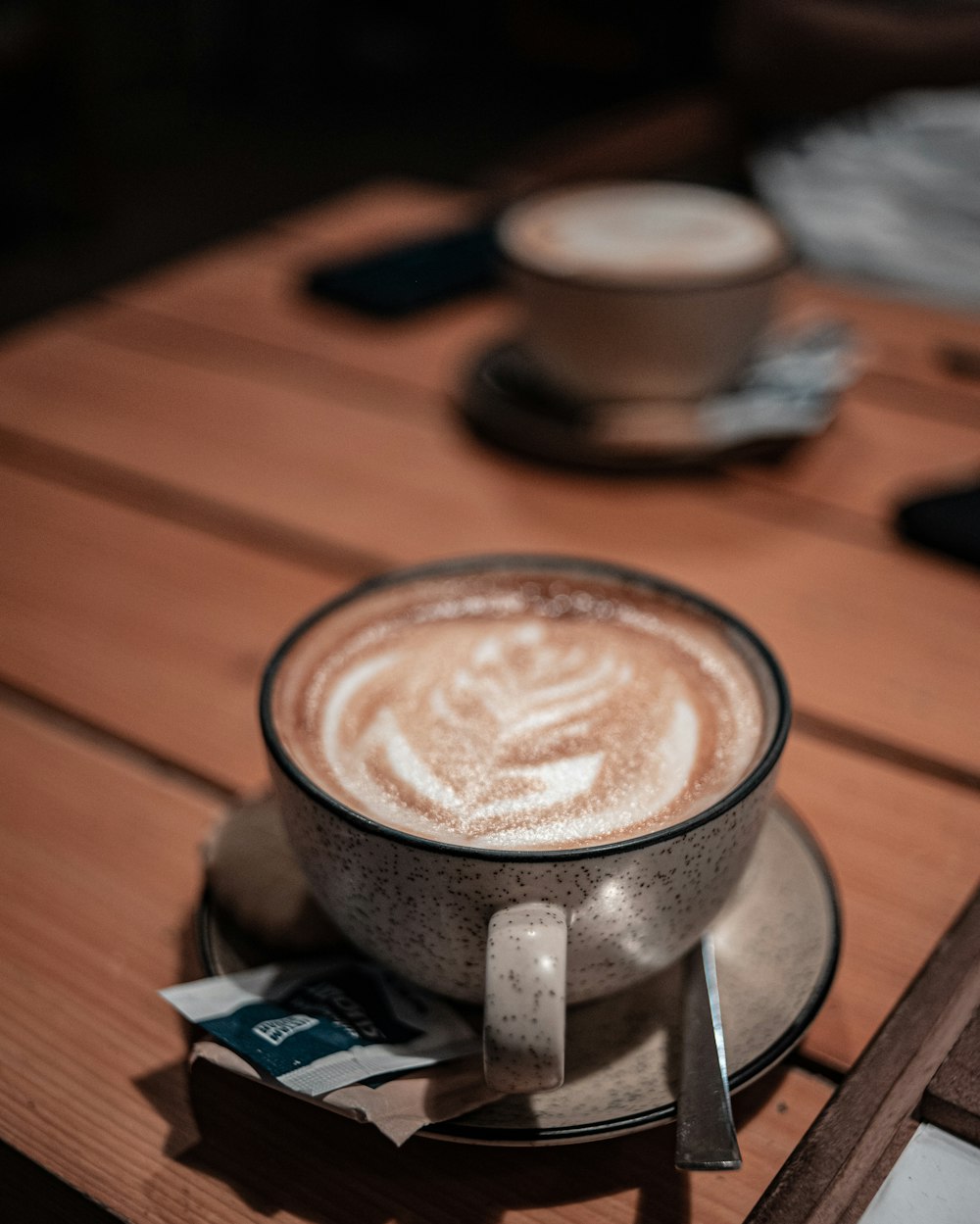 cappuccino in black ceramic mug on brown wooden table