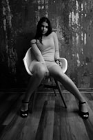 A model seated on a modern chair wearing a stylish monochrome outfit, with subtle accents that bring out the fabric’s texture.