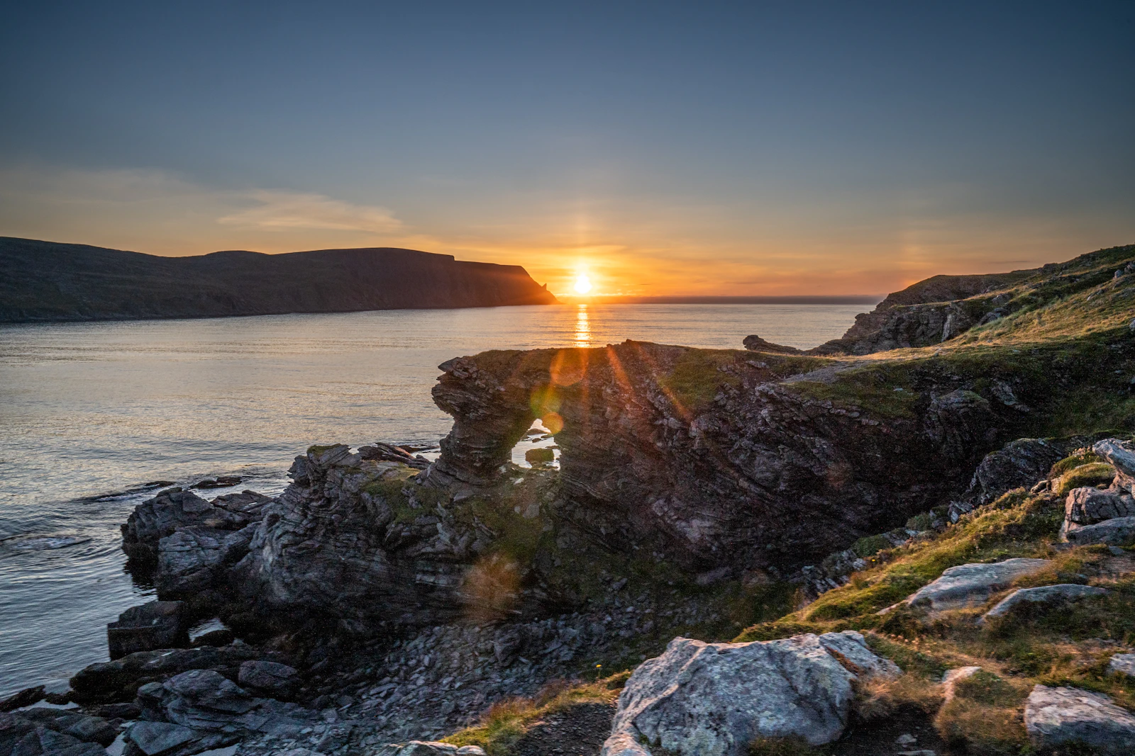 Midnight sun low over the rocky shoreline at Skarsvåg in northern Norway