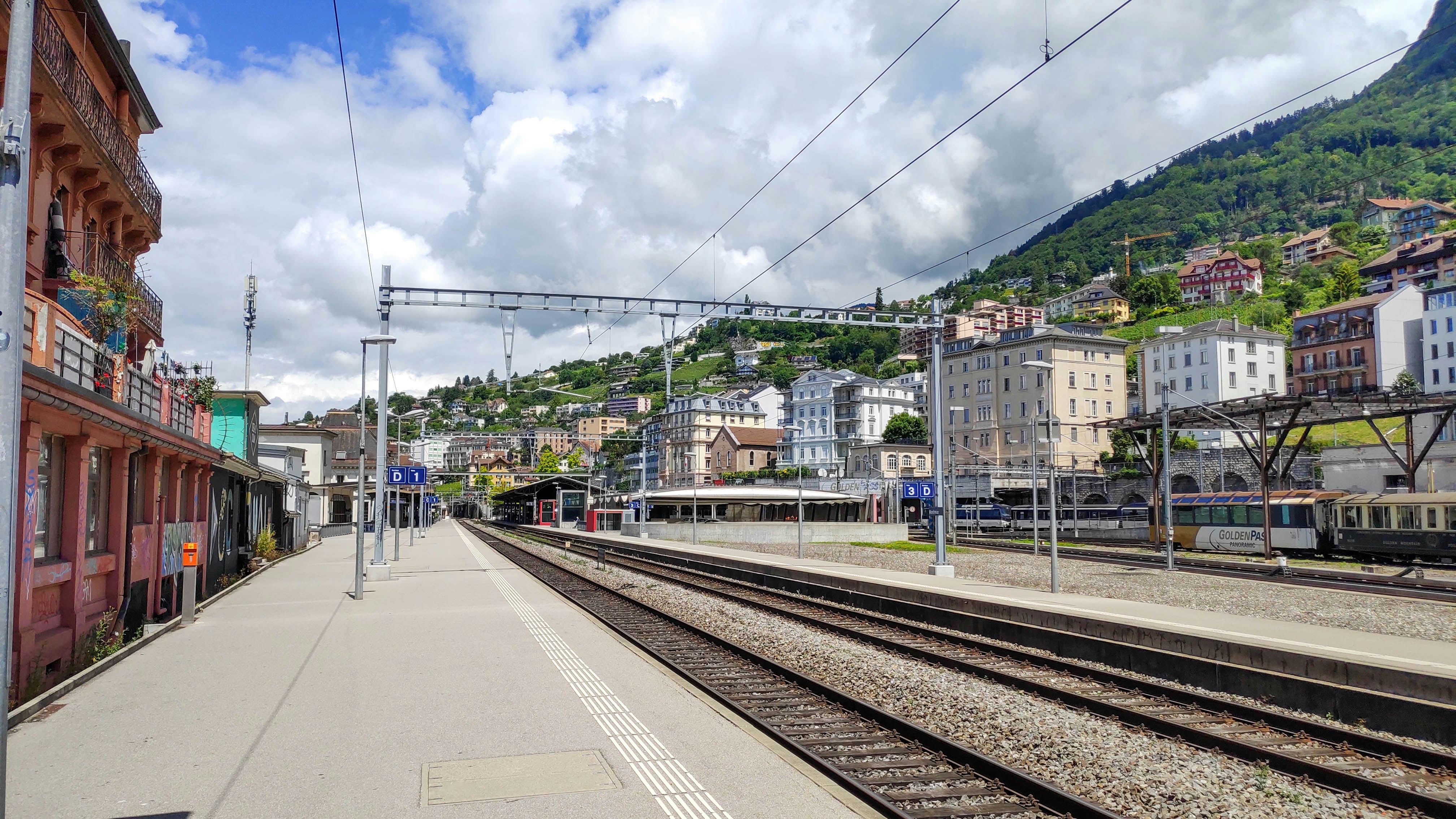 train rail near buildings under white clouds during daytime