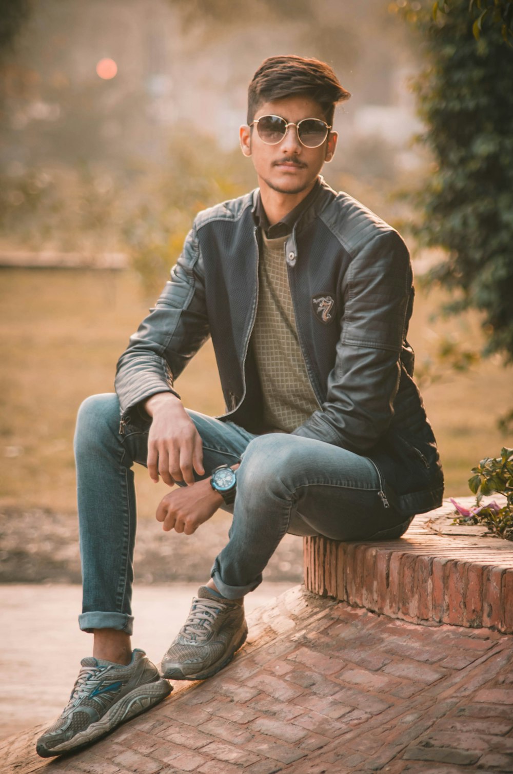 Man in black leather jacket and blue denim jeans sitting on brown concrete  bench during daytime photo – Free Lahore Image on Unsplash