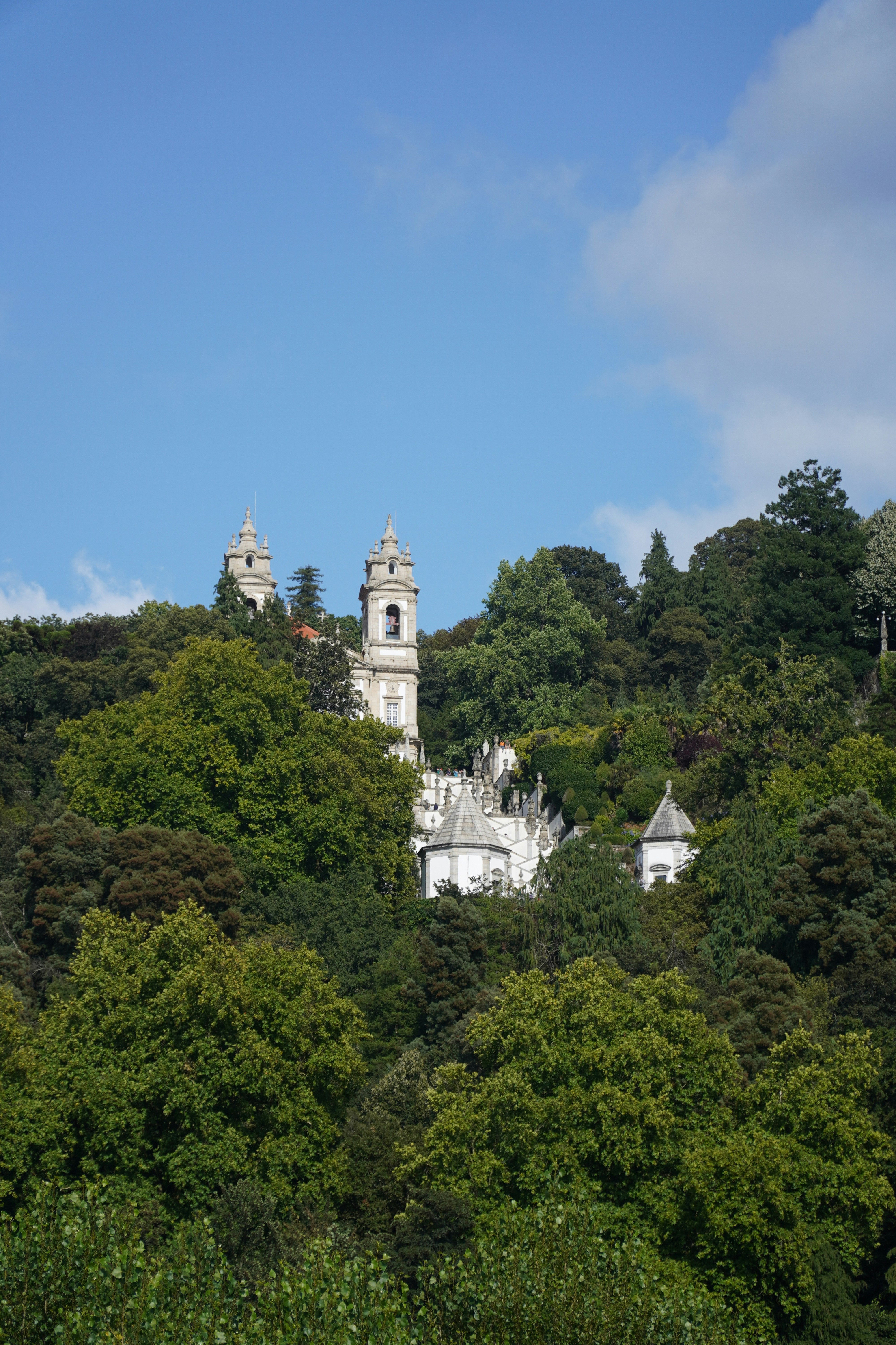 White concrete building surrounded by green trees under blue sky during daytime