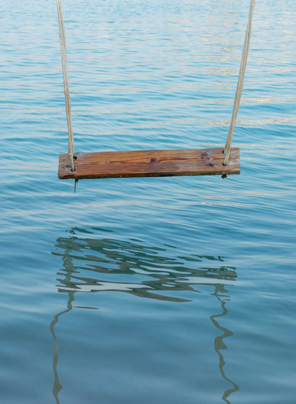 brown wooden swing on body of water during daytime