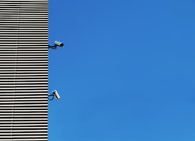 High-definition CCTV cameras installed on a modern building exterior under blue sky.