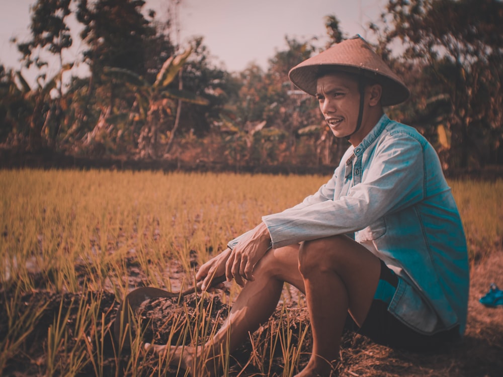 woman in white long sleeve shirt and blue skirt sitting on brown grass field during daytime