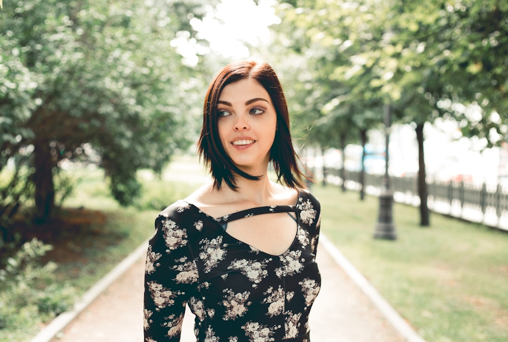 woman in black and white floral dress standing on sidewalk during daytime