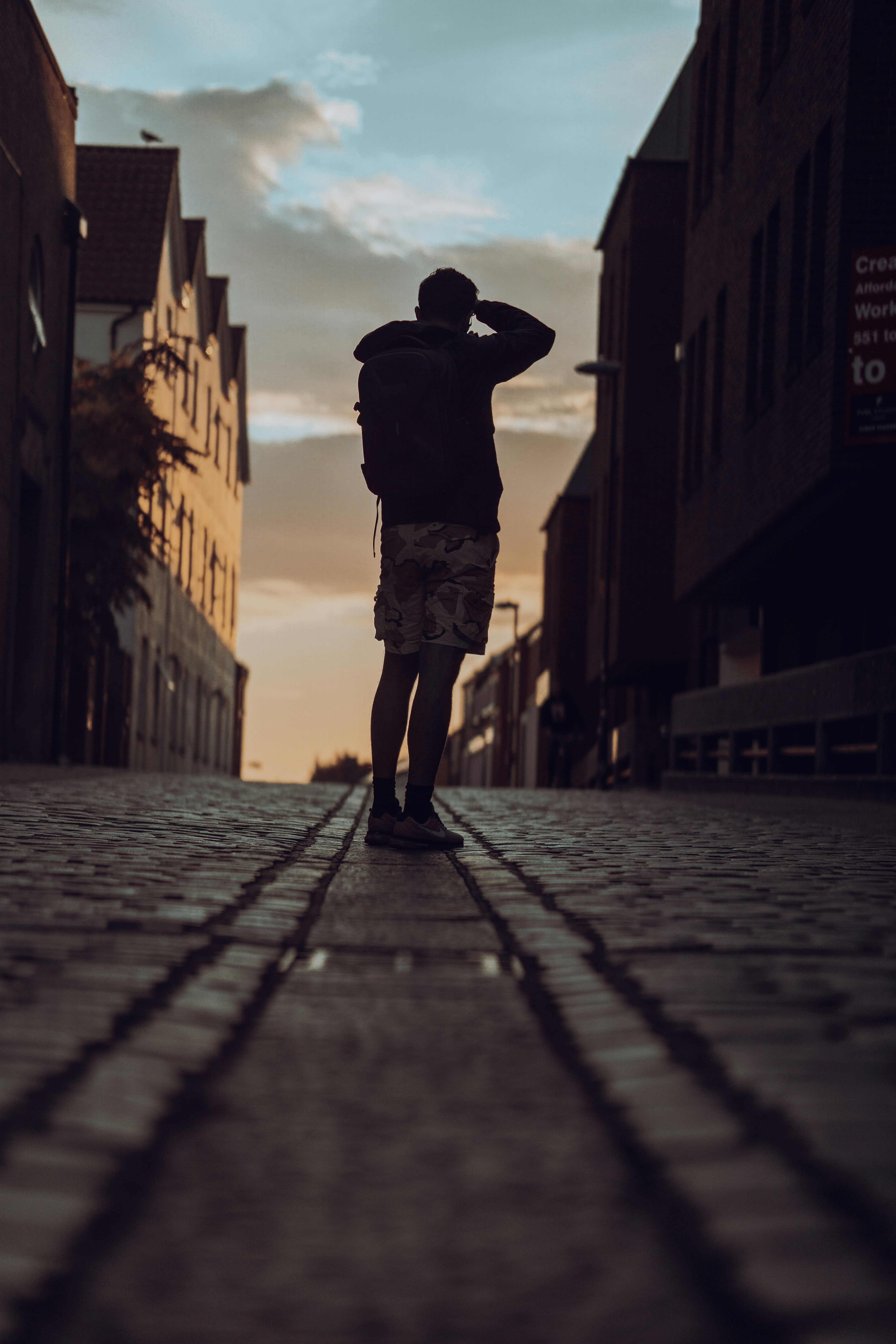 man in black jacket and brown pants standing on sidewalk during daytime