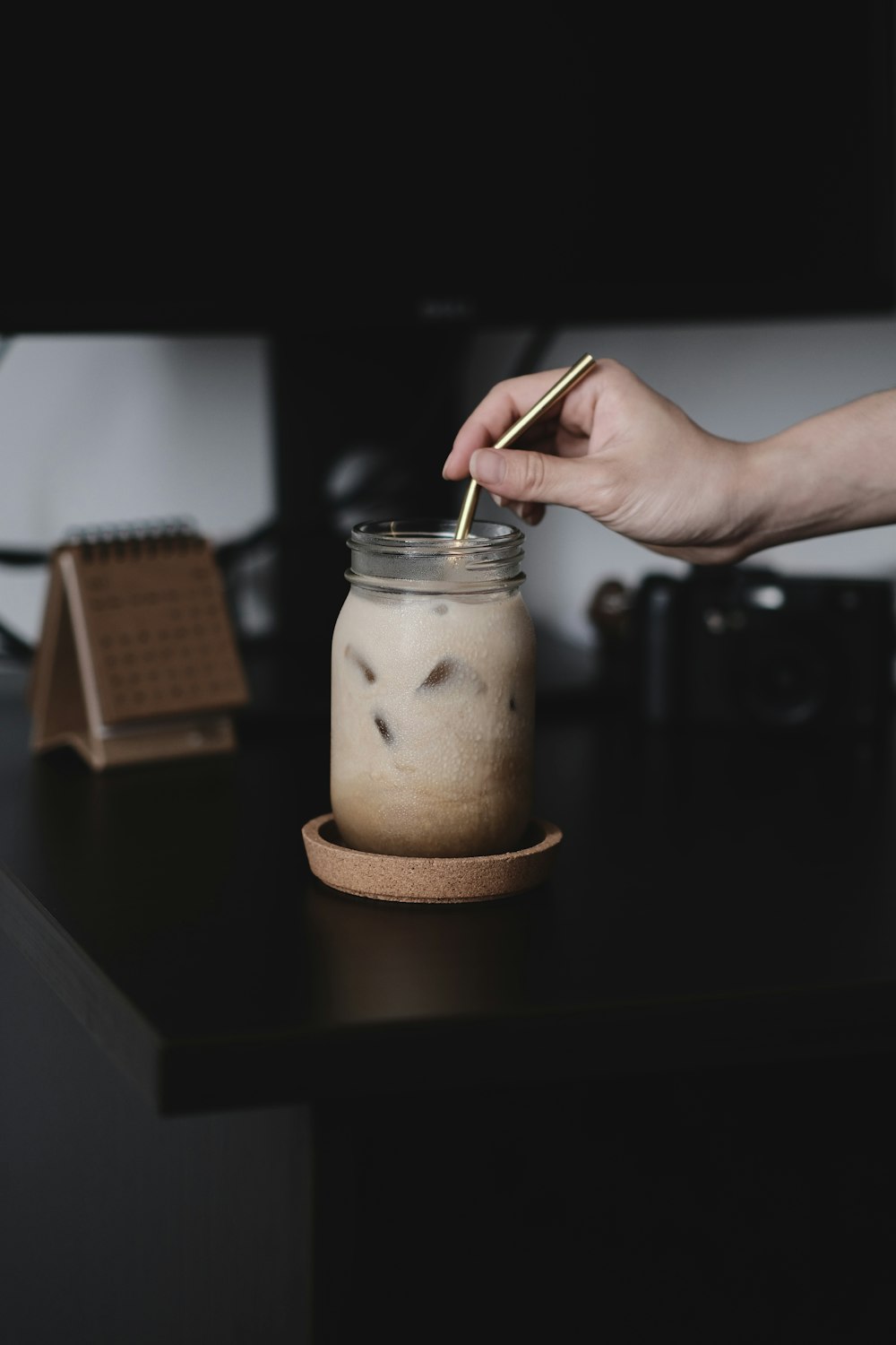 person holding clear glass jar with brown powder