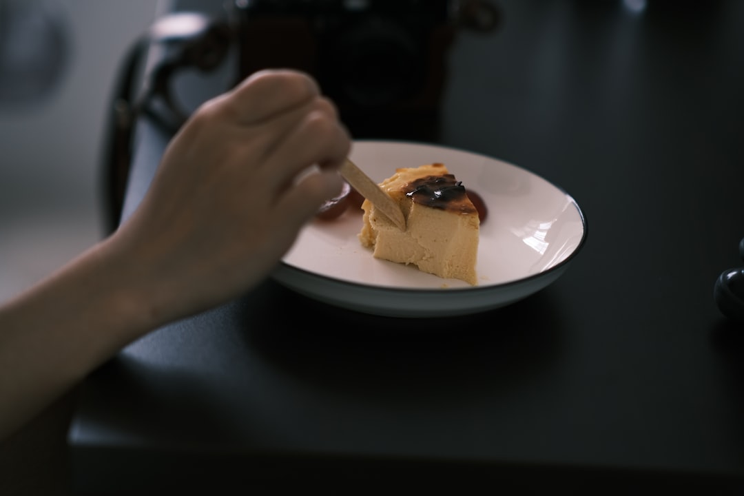 person holding white ceramic plate with brown food