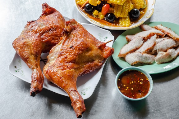 A vibrant spread of assorted dishes including grilled chicken, pasta, sliders, salad, fruit platter, and chocolate mousse on a rustic wooden table.