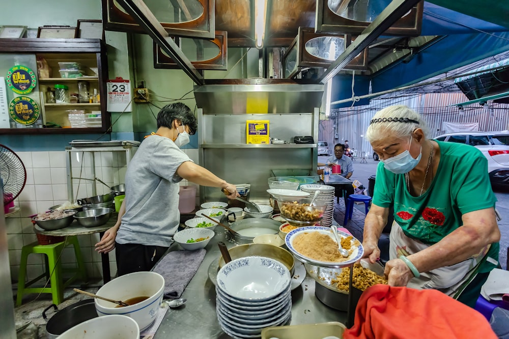 man in white t-shirt and red apron cooking food