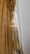 An elegant curtain with intricate tassel tiebacks featuring braided and twisted cords. The fabric has a subtle floral pattern and a smooth texture, draped gracefully to one side.