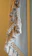 A close-up view of a textile with intricate macramé patterns and numerous fringed tassels in neutral tones. The woven design features a combination of tightly wrapped and loosely knotted textures, creating a sense of handcrafted elegance.