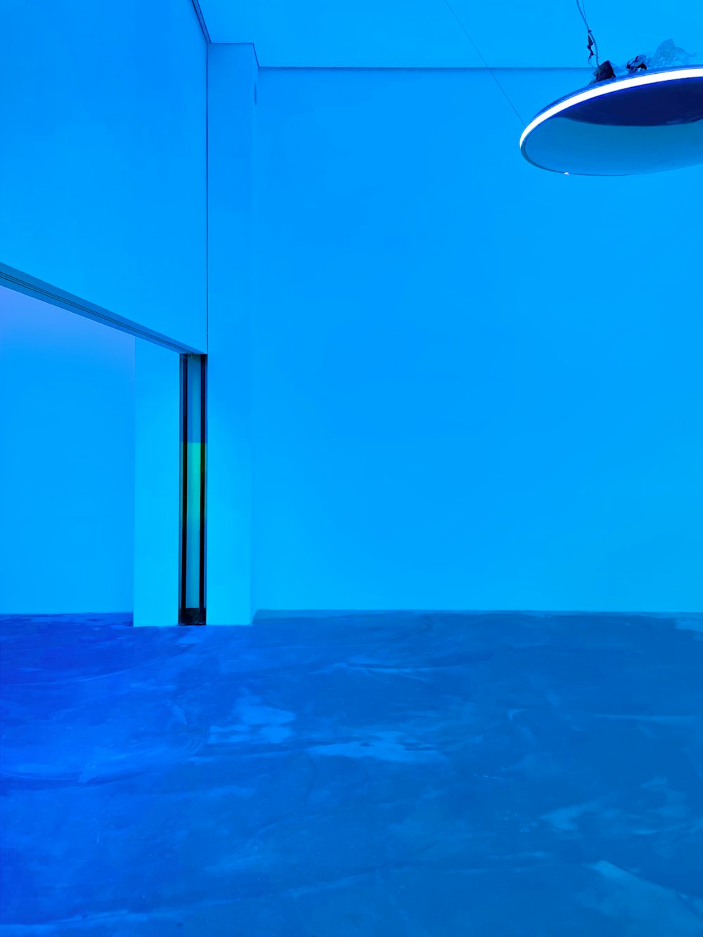 a blue room with a round light hanging from the ceiling
