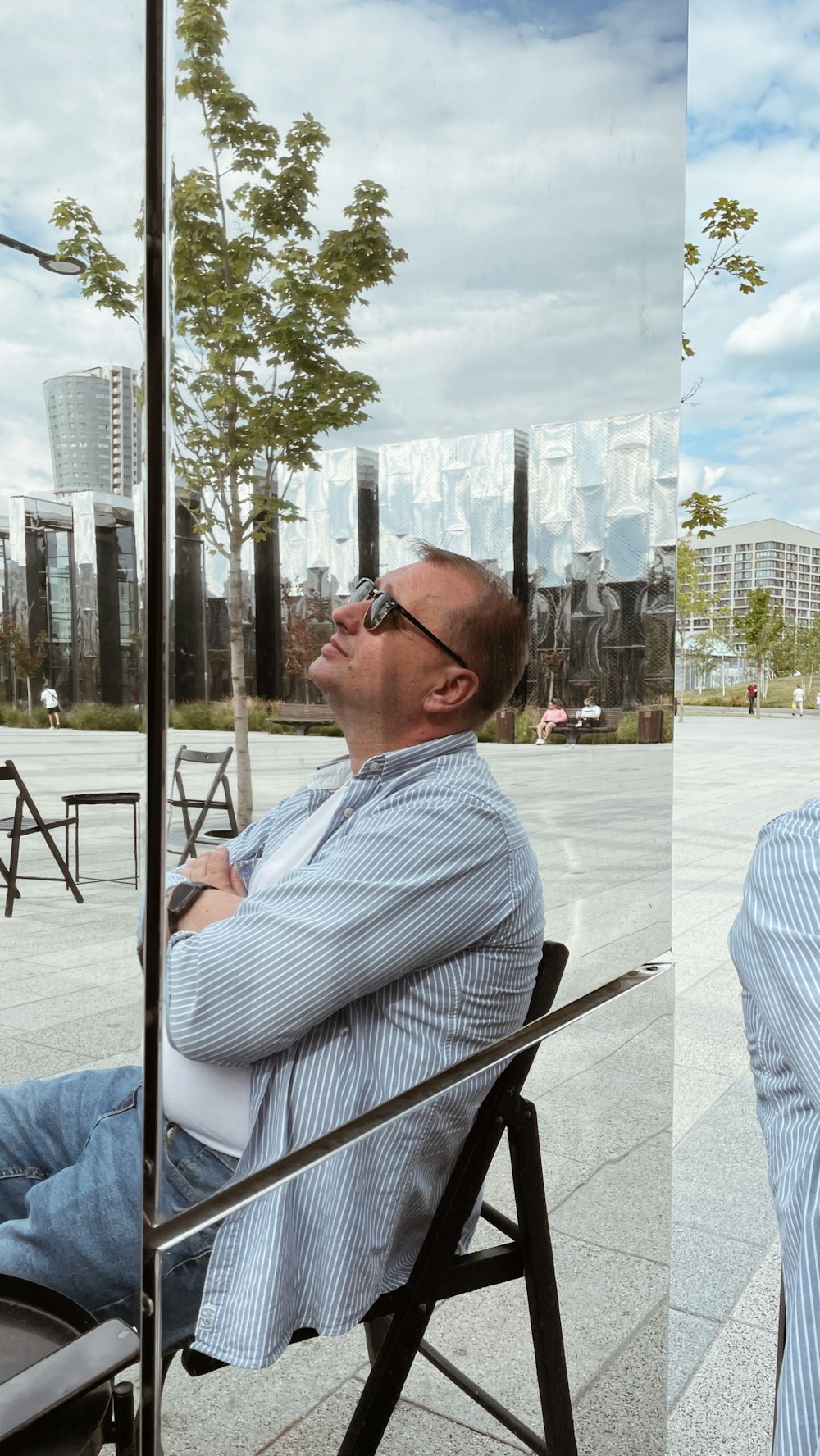 man in white and blue striped dress shirt wearing black sunglasses sitting on chair