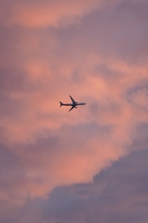 An airplane flying above the clouds during a colorful sunrise.