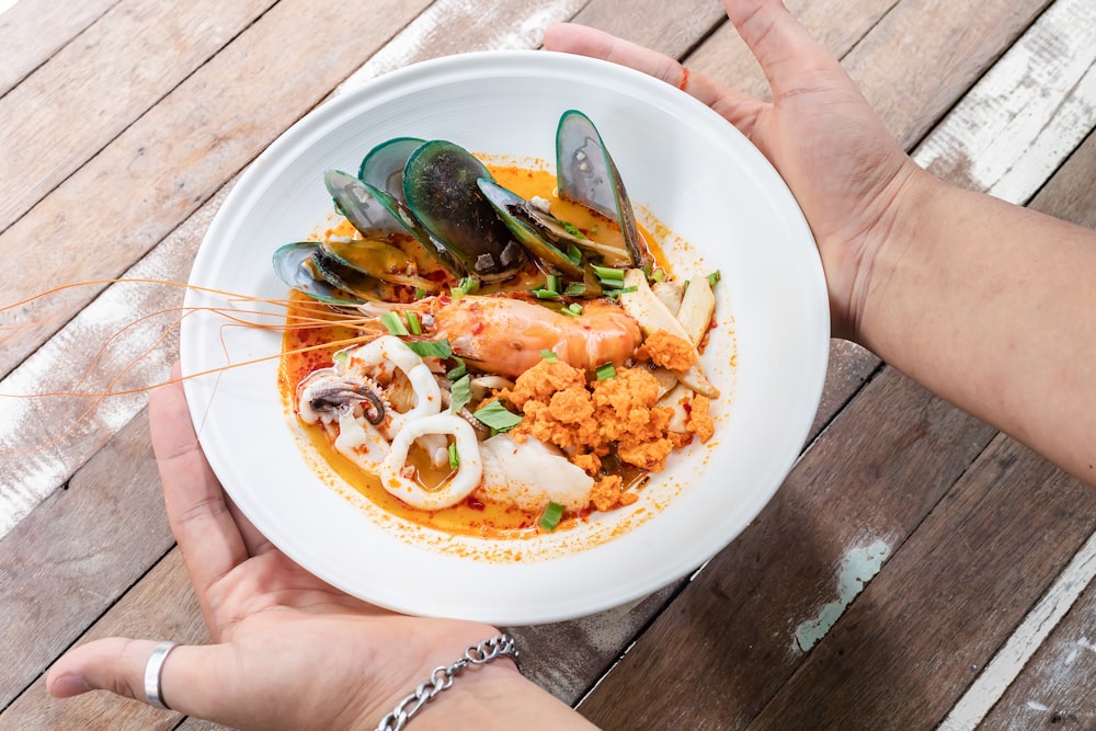 person holding white ceramic plate with food