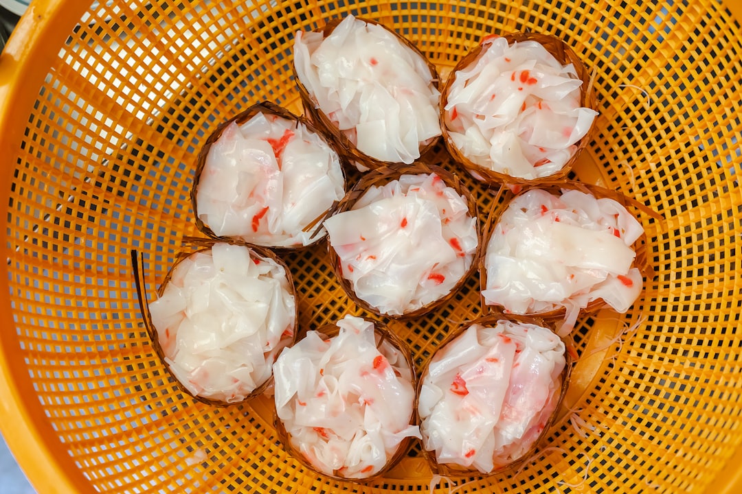 white and red rose petals on brown woven basket, A basket of shrimp-laced rice noodles in Bangkok.