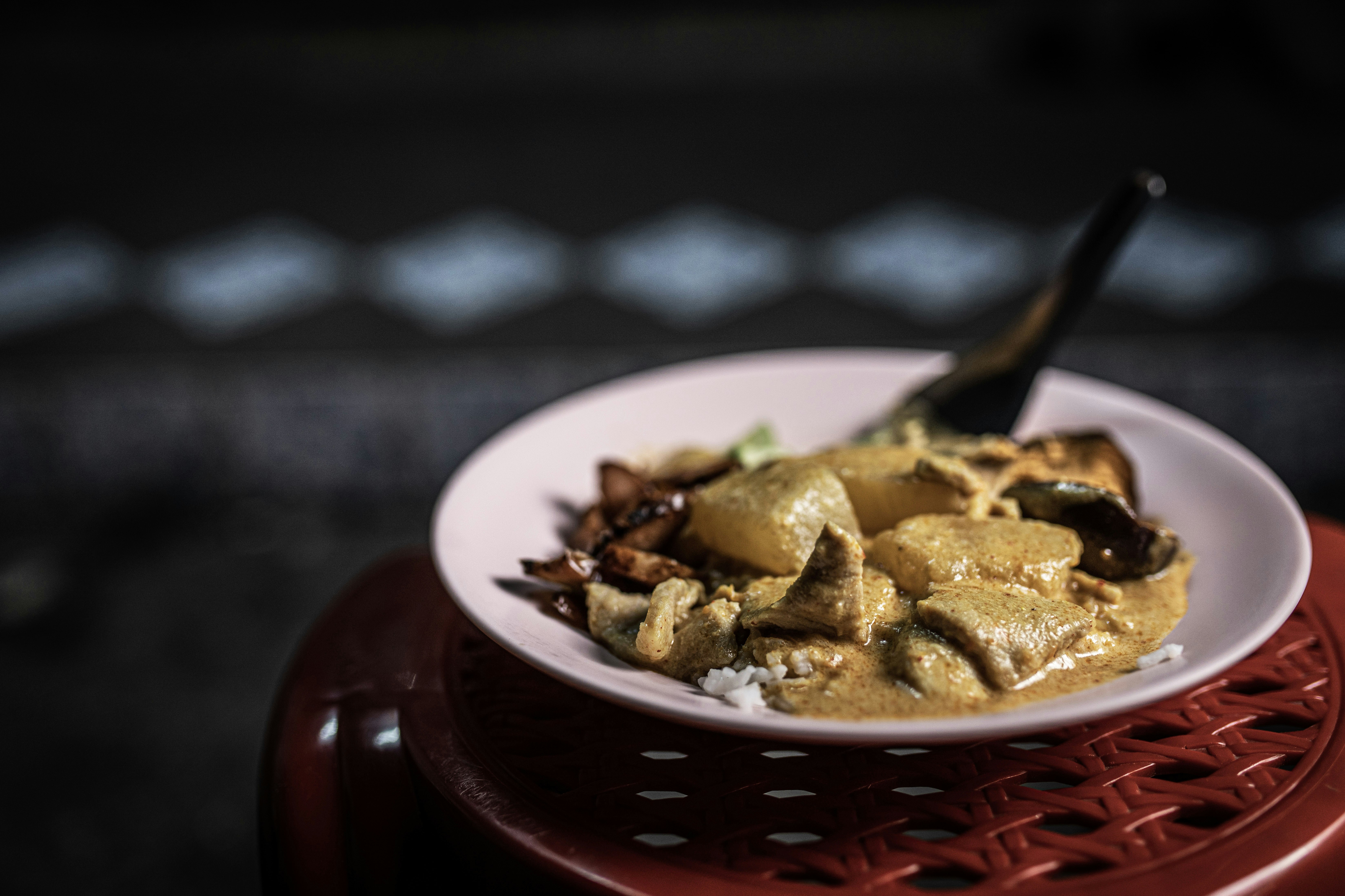 brown and white ceramic bowl with brown food, Yellow curry at the famed Jek Pui Curry Rice in  Bangkok
