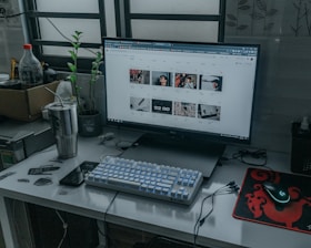 silver imac with white keyboard and silver tumbler