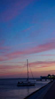 A rescue boat approaching a stranded sailboat on calm waters during sunset.