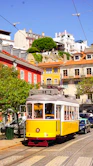 yellow and red tram on road near building during daytime