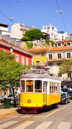 yellow and red tram on road near building during daytime