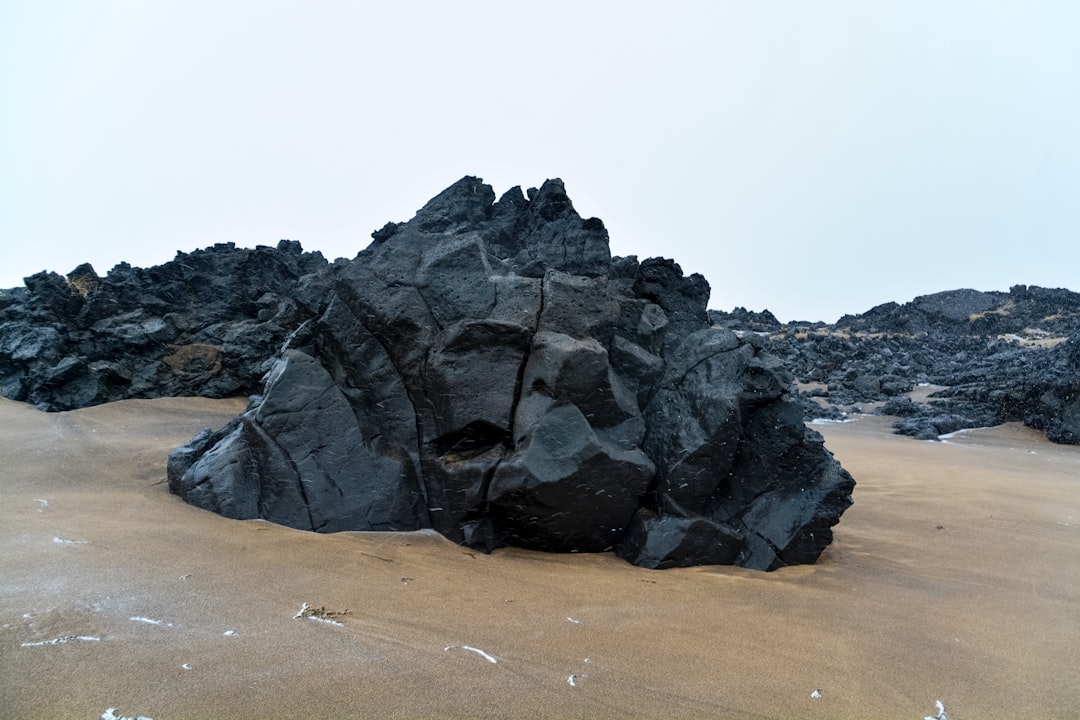 black rock formation on brown sand during daytime