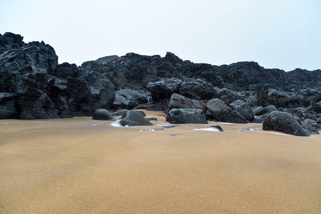 black rock formation on brown sand during daytime
