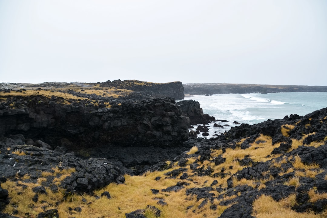 brown rocky mountain beside sea during daytime